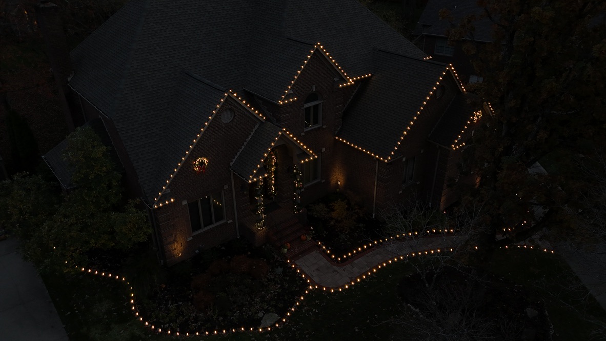 Aerial view of a home roofline and lit walkway at night