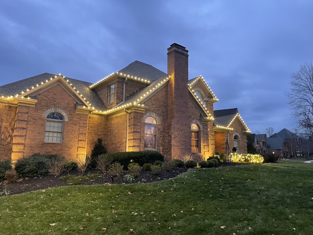 Brick home with roofline lights and uplighting at dusk