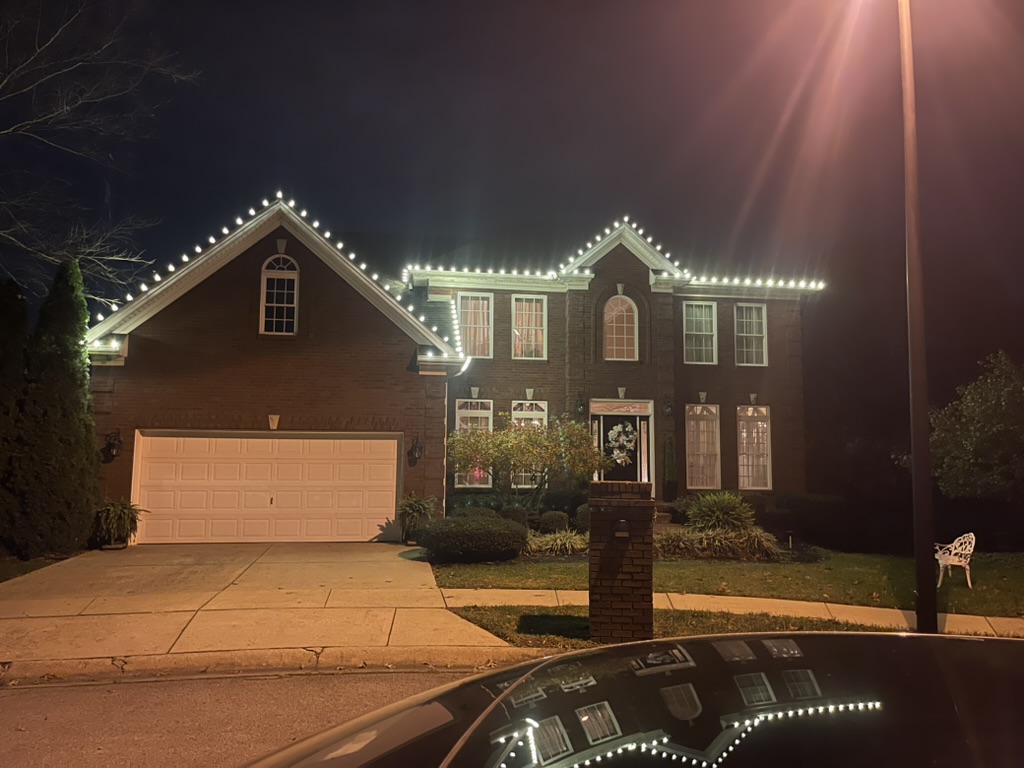 Brick colonial home with warm-white roofline lights at night
