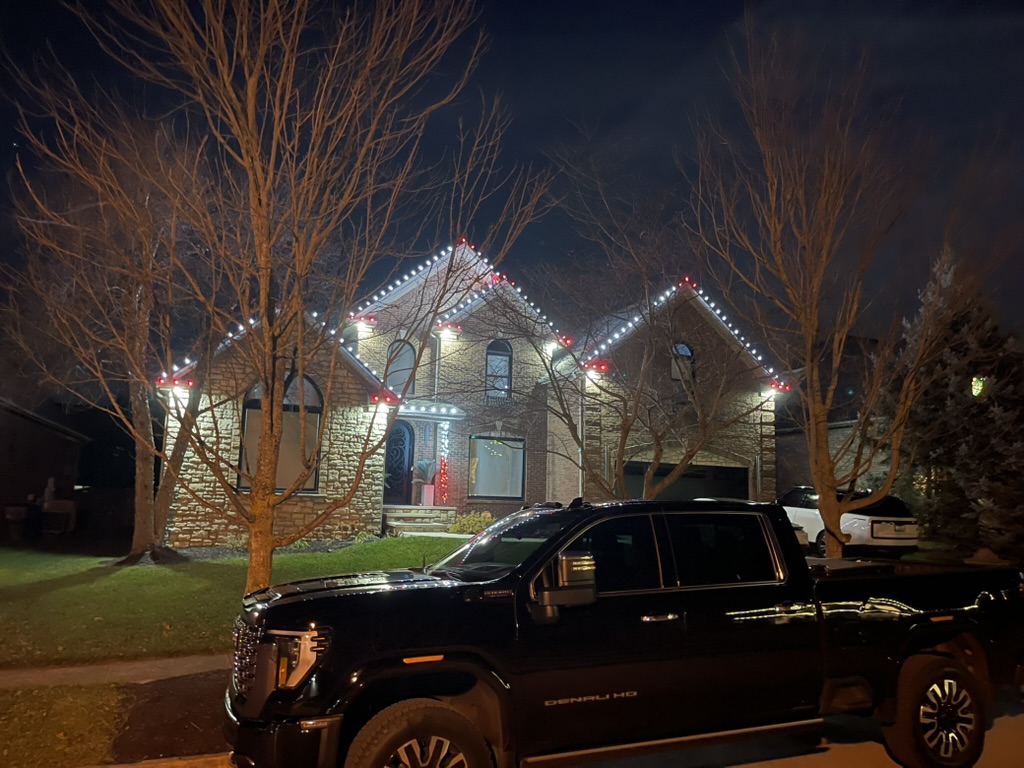 Brick home with red-and-white candy-cane roofline lights at night
