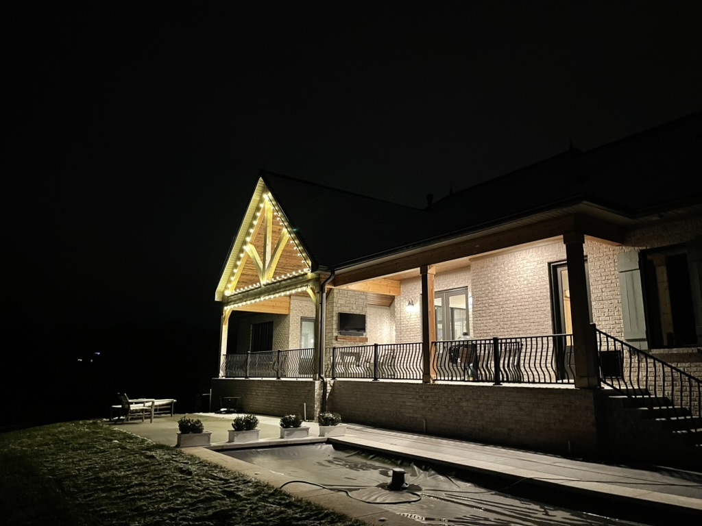 Covered porch and gable outlined in warm-white lights at night