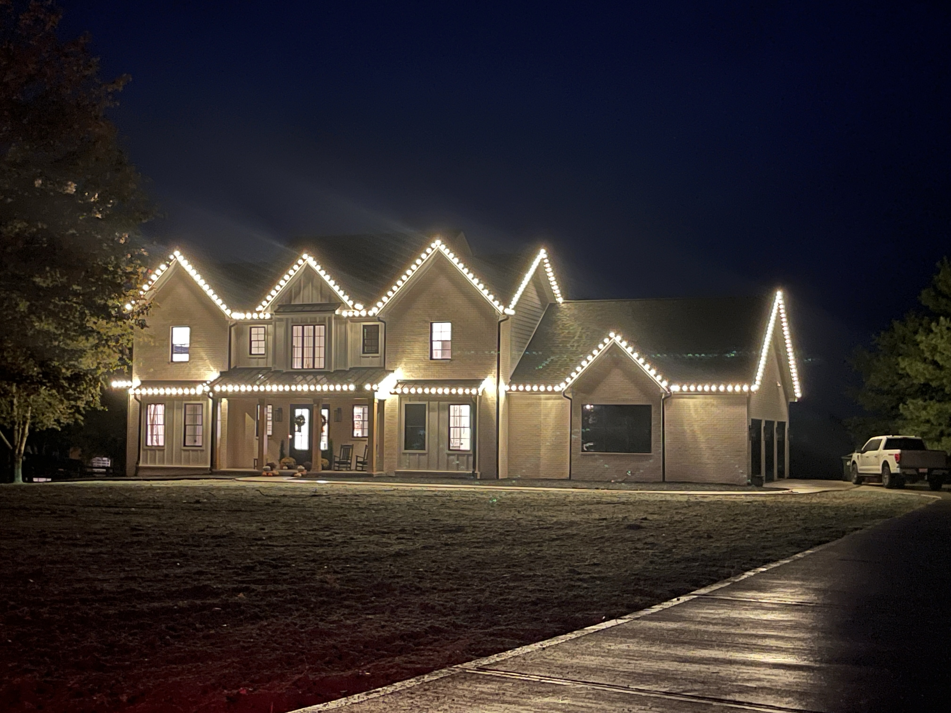 Two-story farmhouse with roofline C9 lights at night