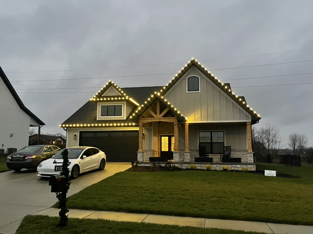 Modern gray farmhouse with warm-white roofline lights at dusk