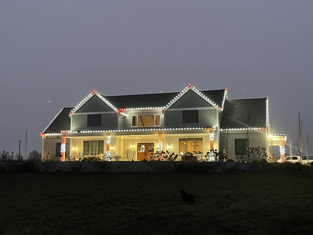 Ranch home with warm-white roofline and red accent lights at dusk
