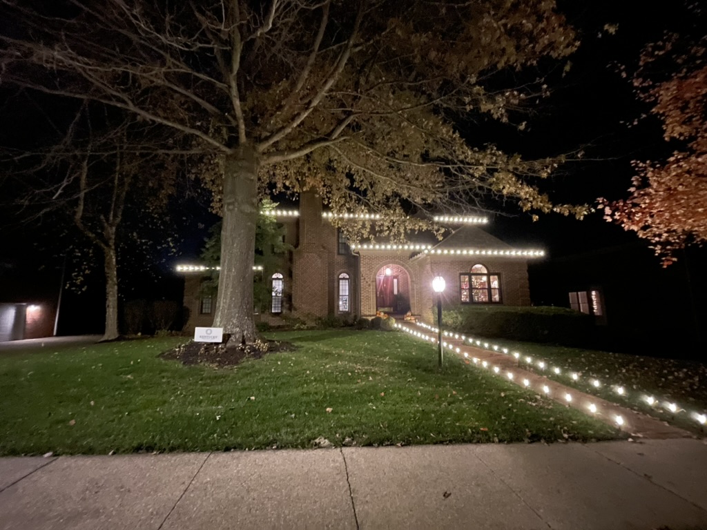 Brick home with roofline and walkway path lights at night