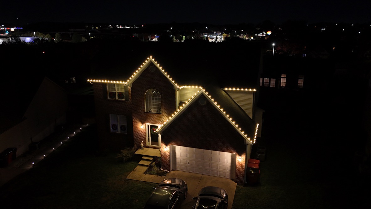 Two-story brick home with warm-white C9 roofline lights at night