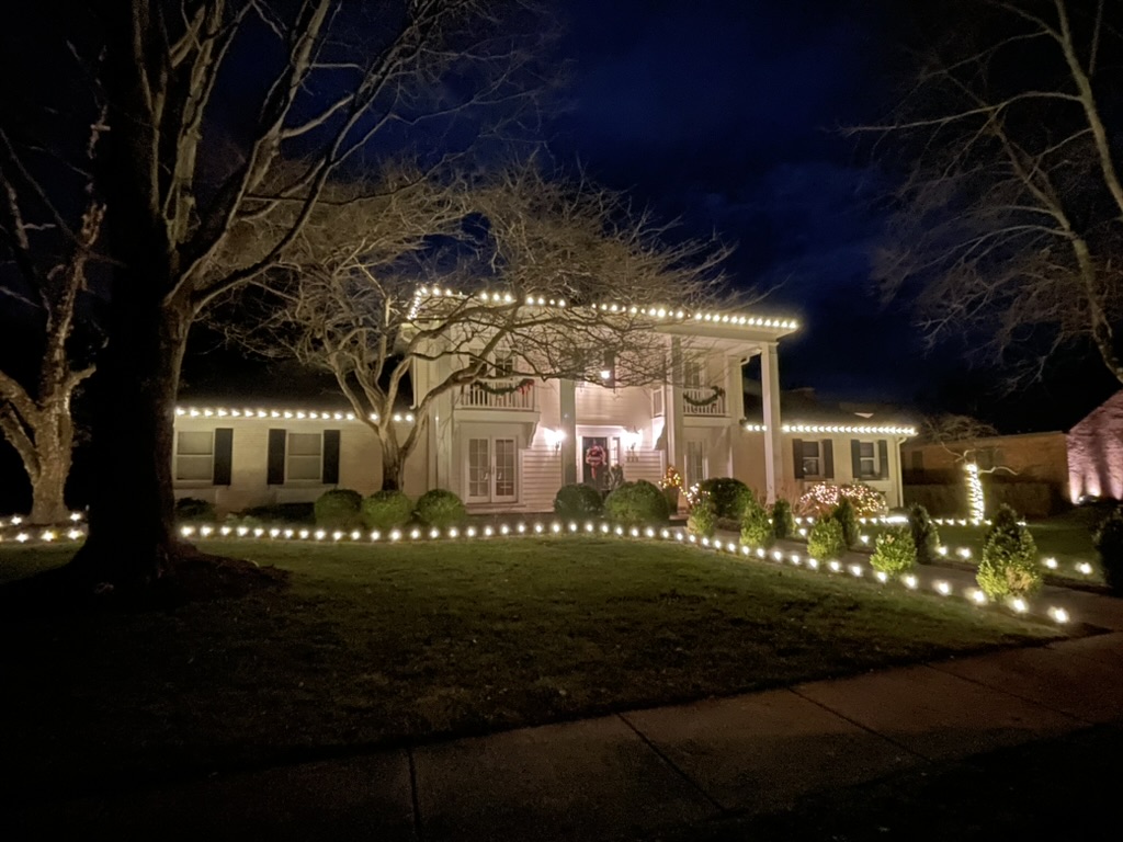 Historic white home with pergola, roofline and walkway path lights at night